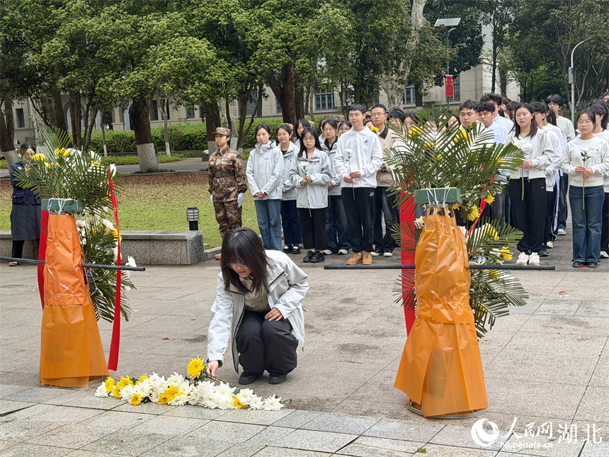 师生向革命烈士恽代英同志敬献鲜花、俯身鞠躬。