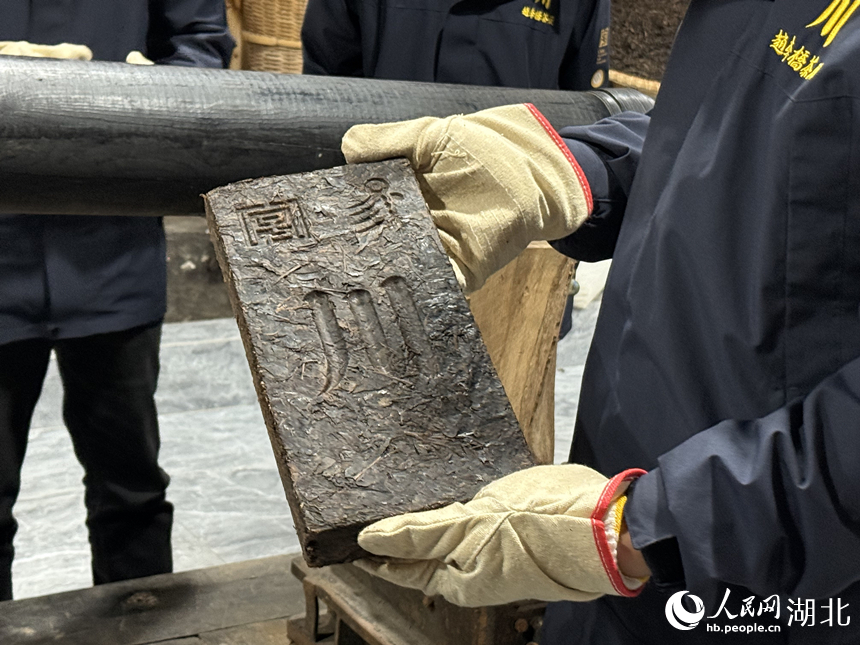 匠人向记者展示印有“川”字的青砖茶。人民网记者 周恬摄