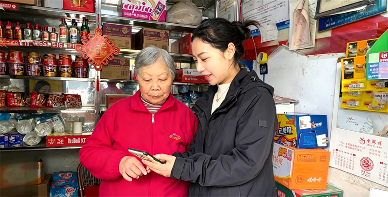 长阳烟草工作人员（右）指导零售户使用智能软件。