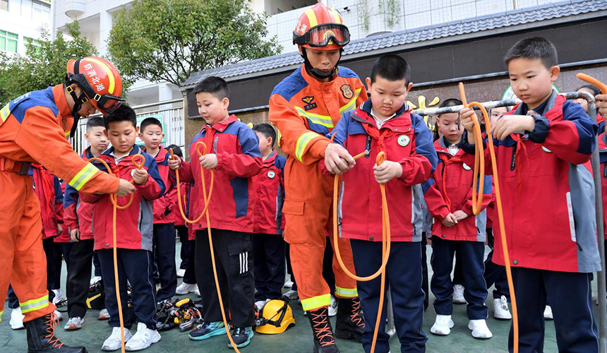 在襄阳市保康县城关镇小学，消防员手把手指导学生打消防绳结。杨韬摄