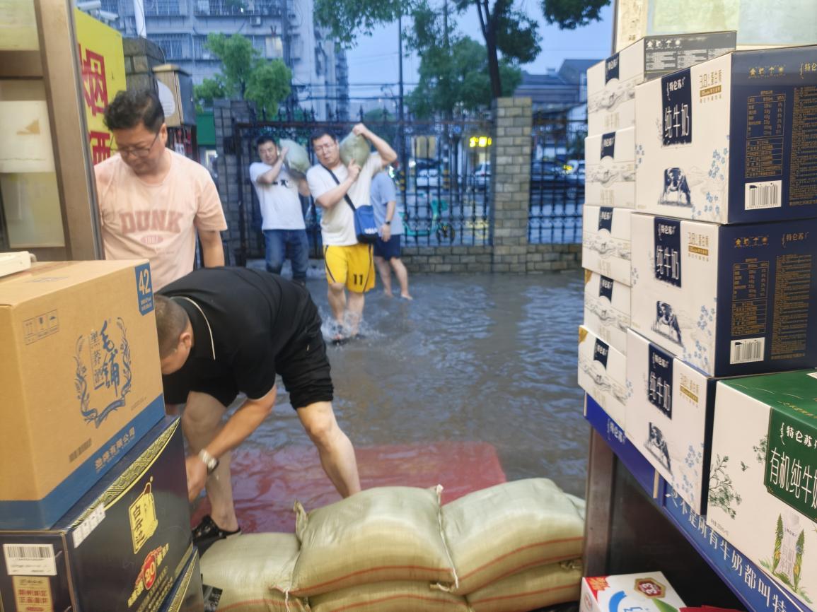 沙市區局（營銷部）救援小組成員用沙袋封堵店鋪前門，阻止雨水倒灌（沙市區局 陳麗群攝）