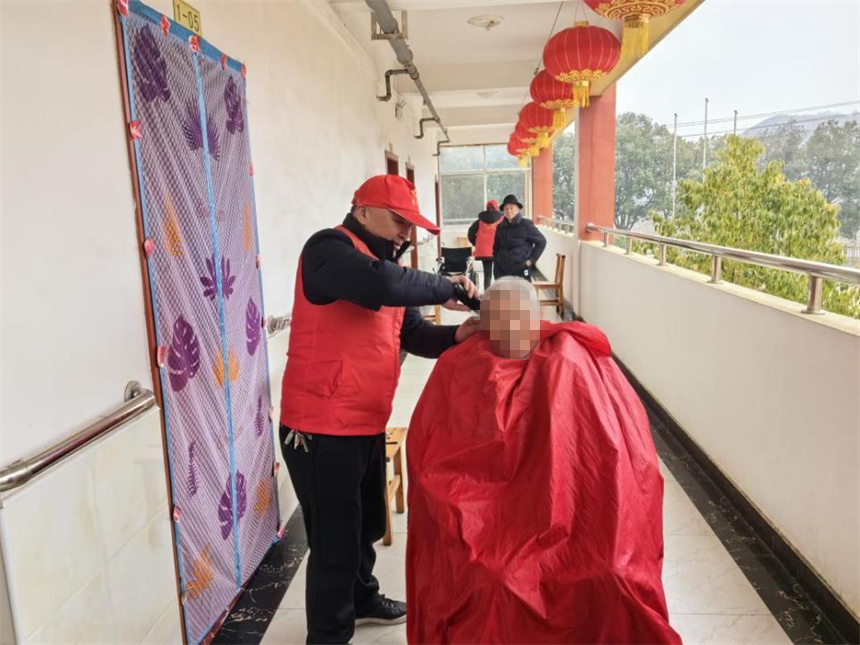 志愿者冷胜安为老人理发。