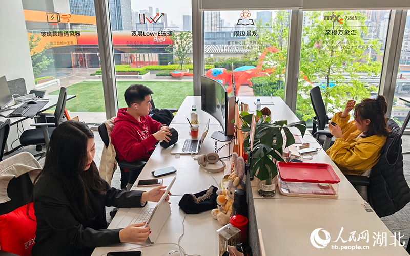 滨江亲橙人工智能OPC社区内，翁多嘉和丈夫魏煜朋在工位（左侧）忙碌。人民网记者 周雯摄