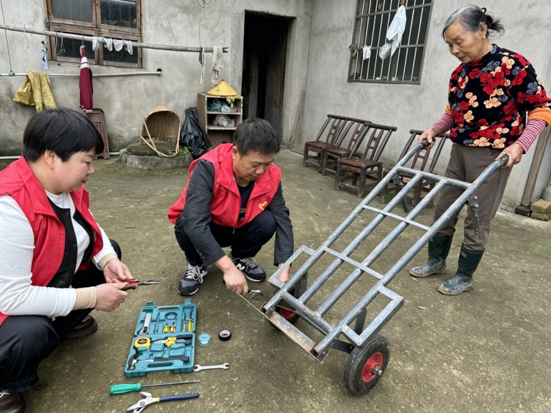 驻村工作队员为老人修推车。