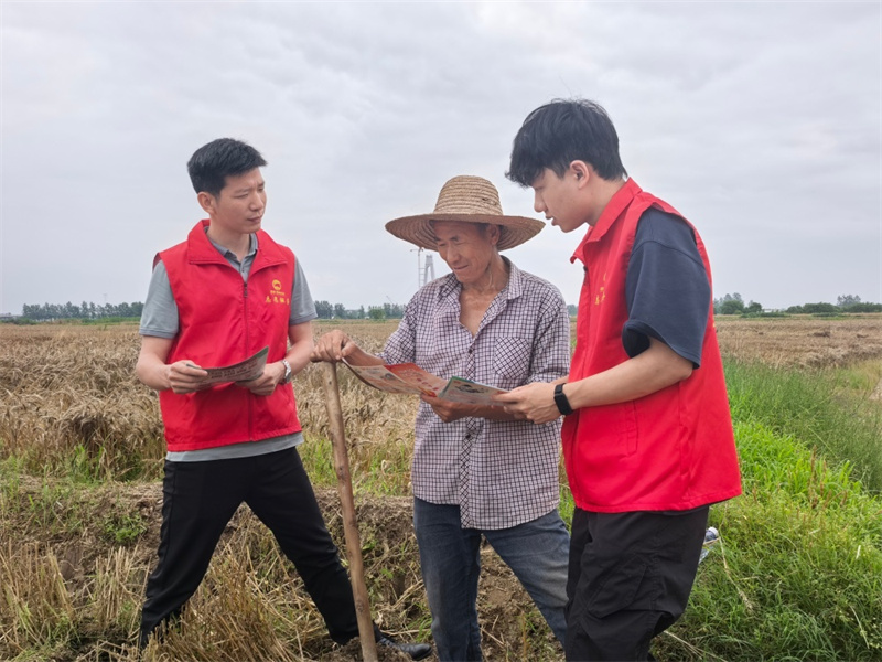 工作人员向农忙大爷宣讲民法典知识。