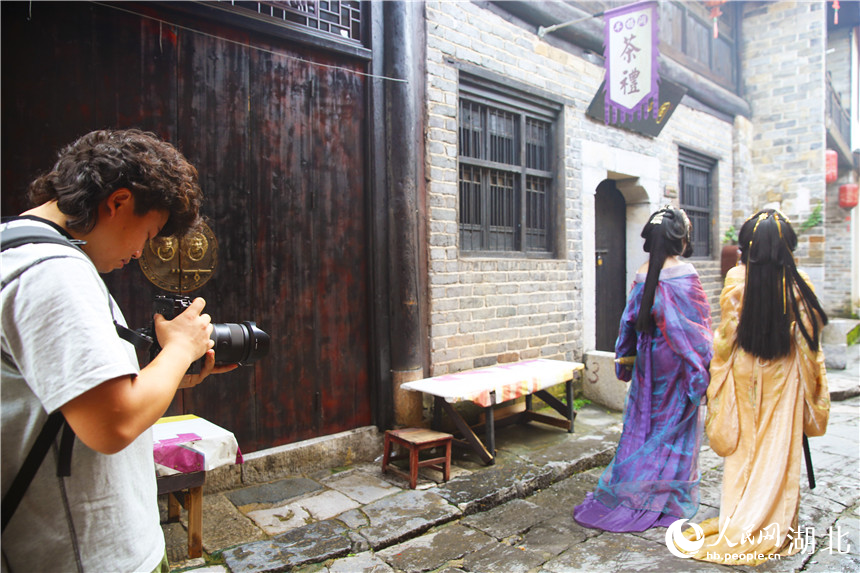 兼职摄影师熊威正在给游客拍照。人民网记者 王郭骥摄