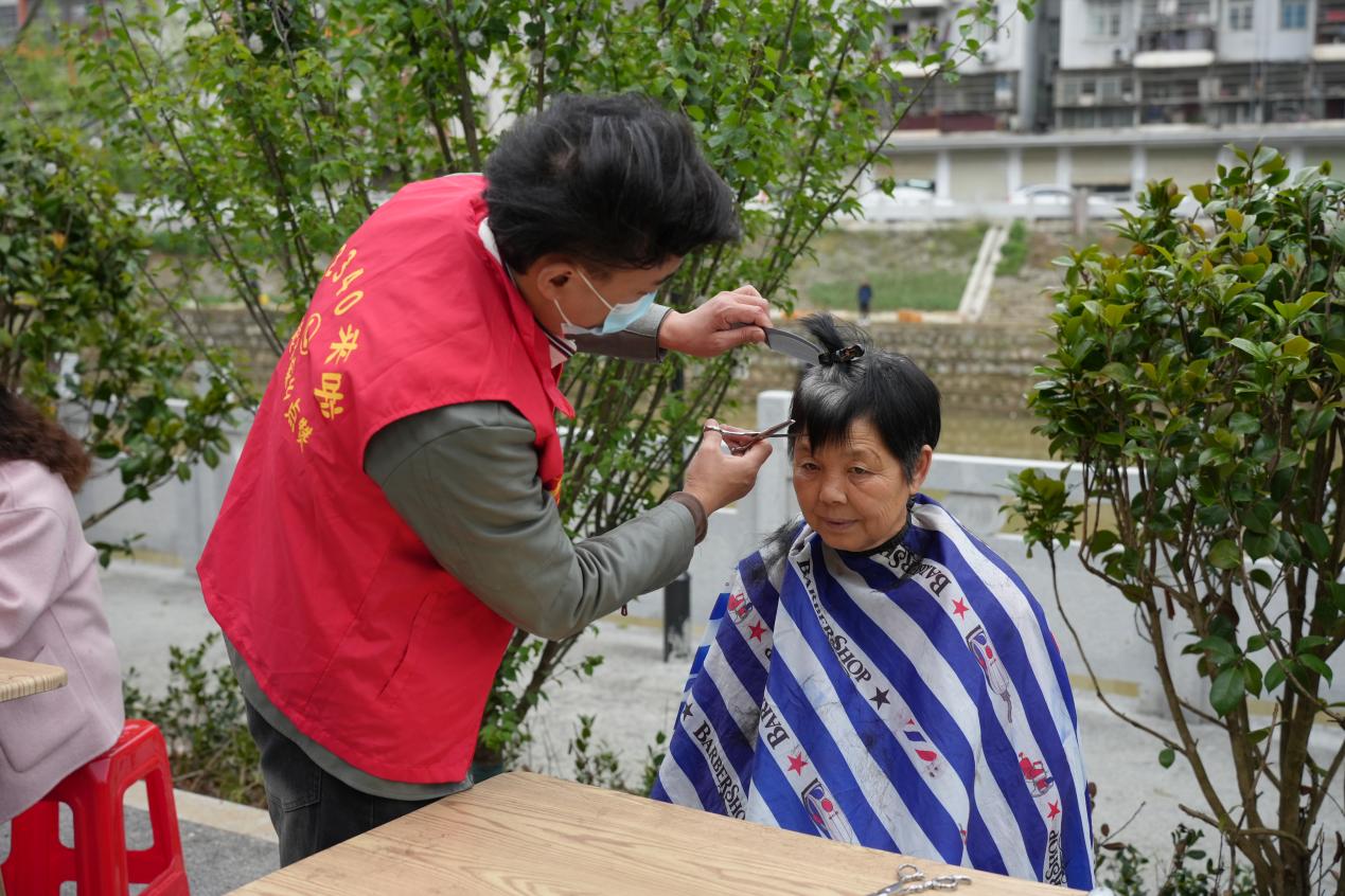 义剪摊位为老人剪头发。