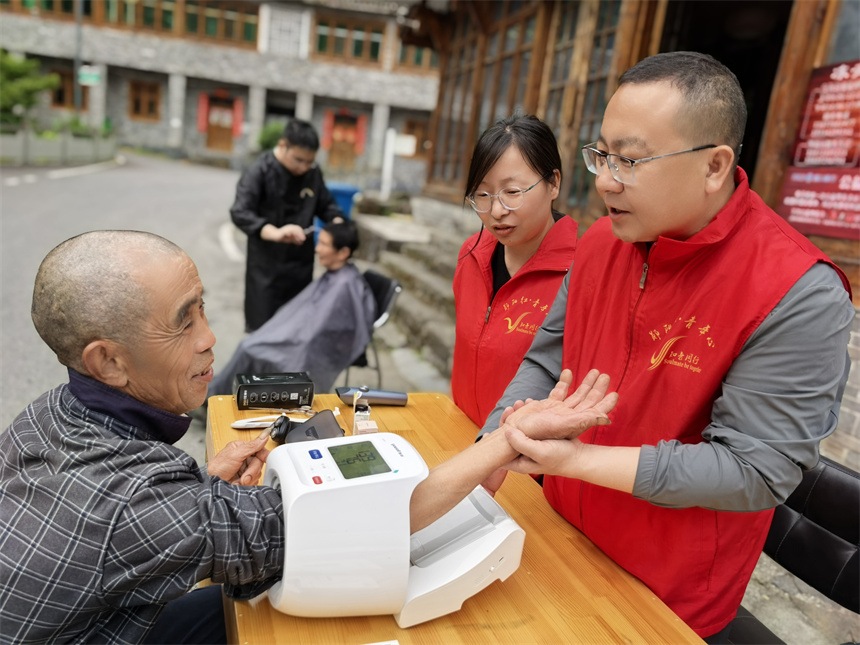 志願者幫助老人量血壓。