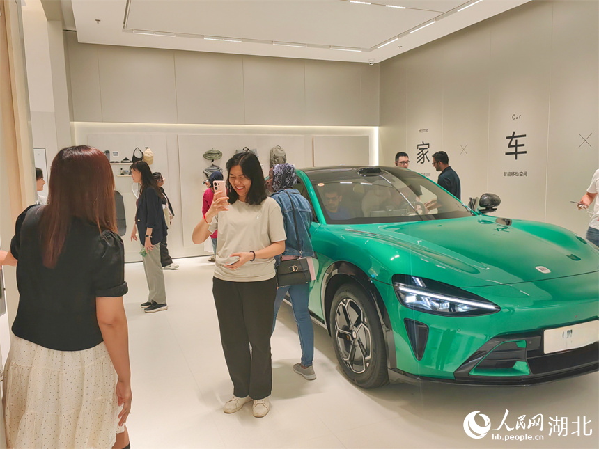国外青年代表与中国产的电动汽车合影留念。人民网记者 郭婷婷