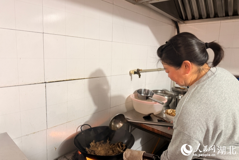 丘小跃在后厨炒菜。人民网记者 张隽摄