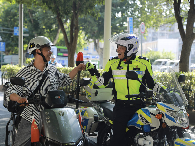 襄阳交警曾怀庆在巡逻途中劝导群众。
