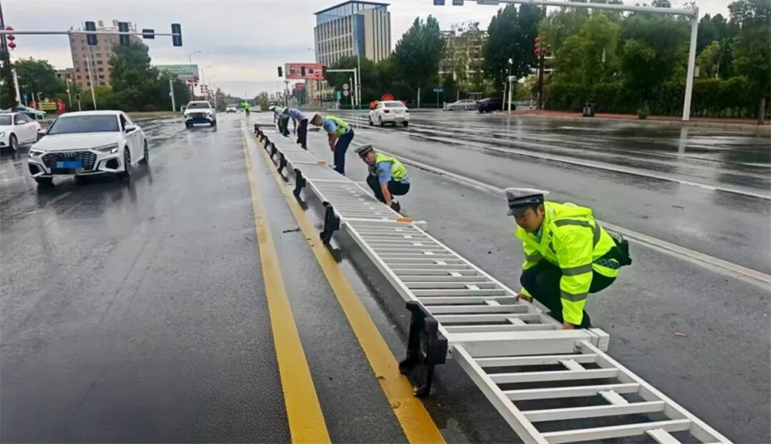 黃岡交警冒雨在黃梅城區晉梅大道將被大風刮倒的護欄及時扶正，守護道路通行秩序。