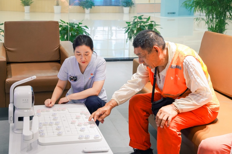在中国移动“AI清凉驿站”，户外劳动者与AI机器人进行对弈。