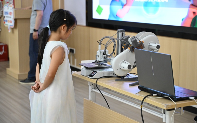 孩子观摩3D打印机运行。