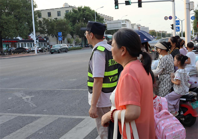 义警队员引导学生安全通过马路。