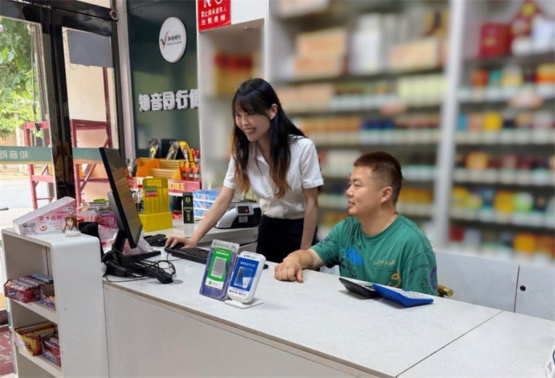 青年員工梅真妍指導零售戶使用終端系統。